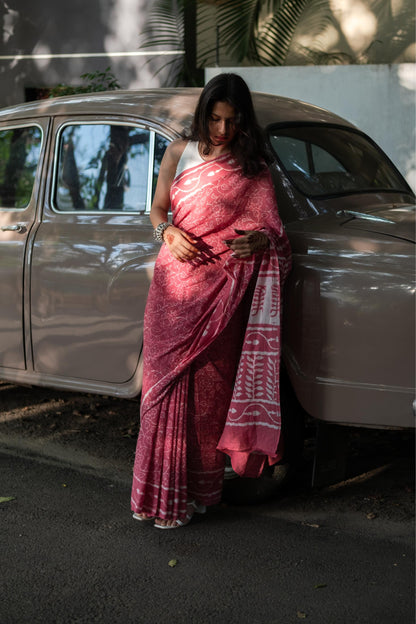 Woman in a pink saree standing next to a vintage car