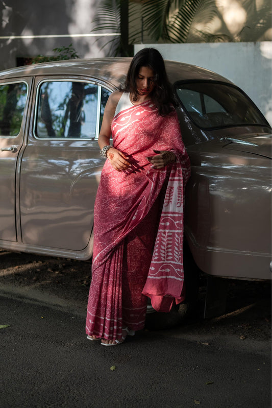 Woman in a pink saree standing next to a vintage car