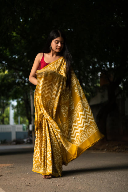 Woman in a yellow saree with a red blouse walking outdoors.