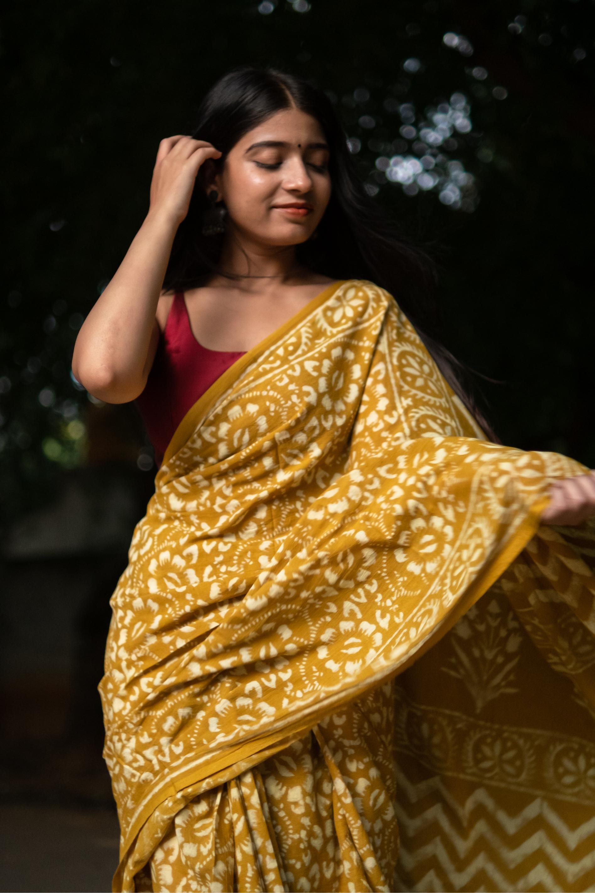 Woman wearing a yellow saree with a dark background